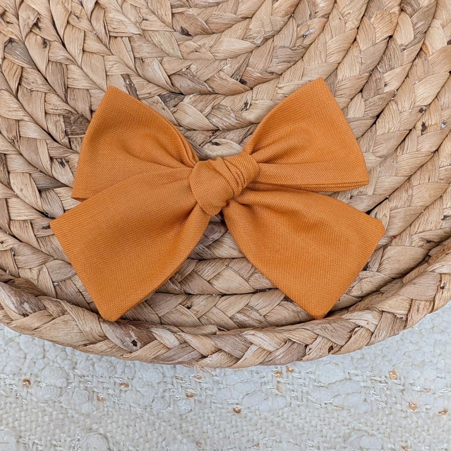 Orange bow on a woven surface