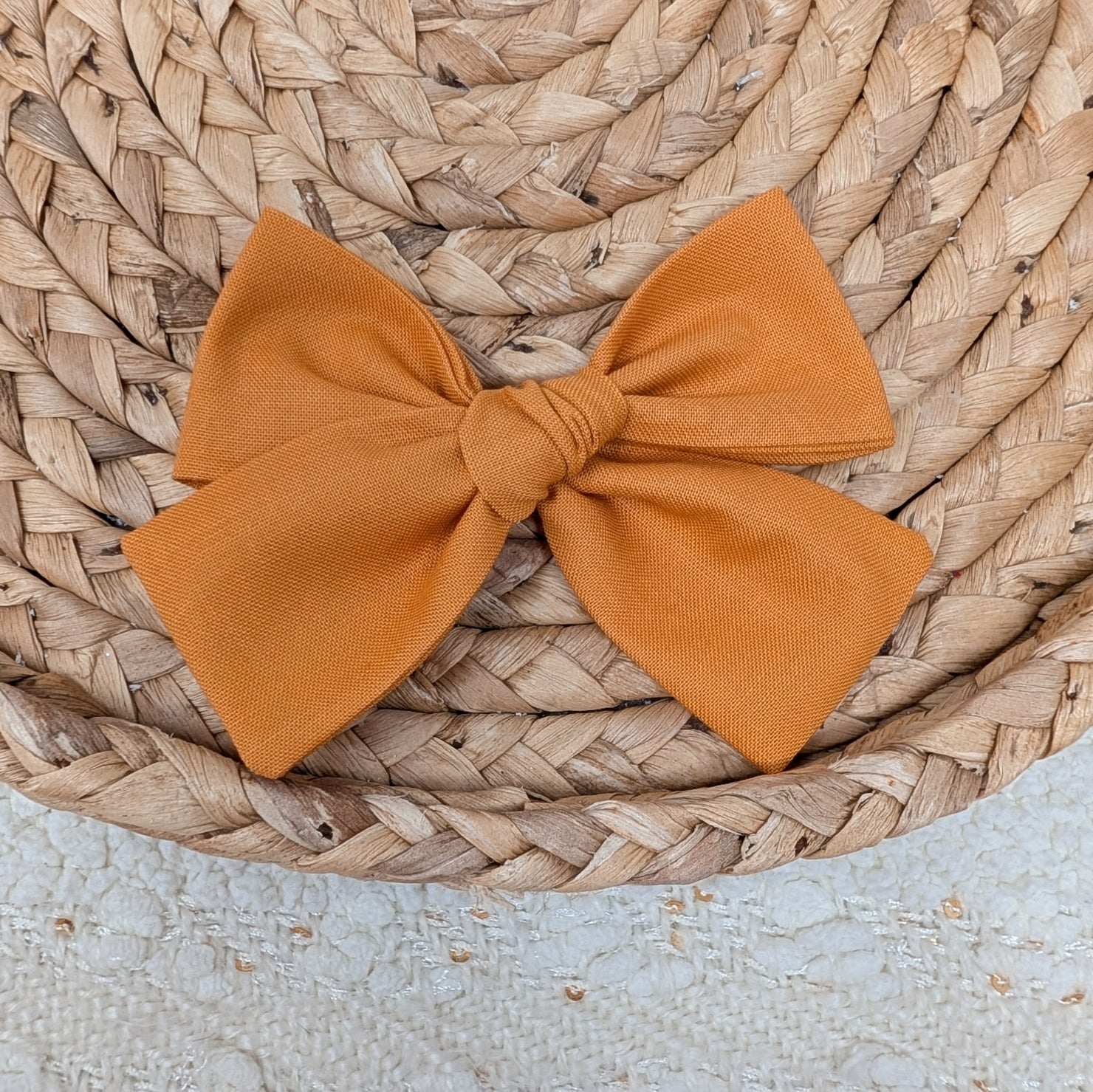 Orange bow on a woven surface