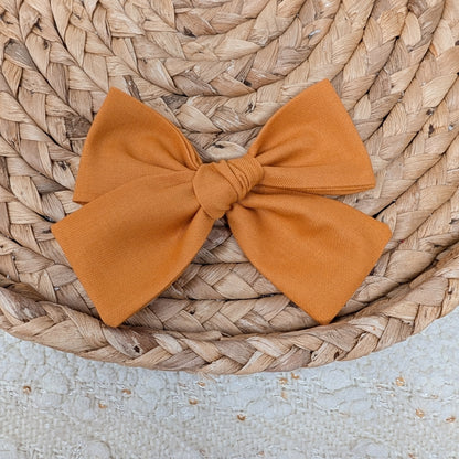 Orange bow on a woven surface