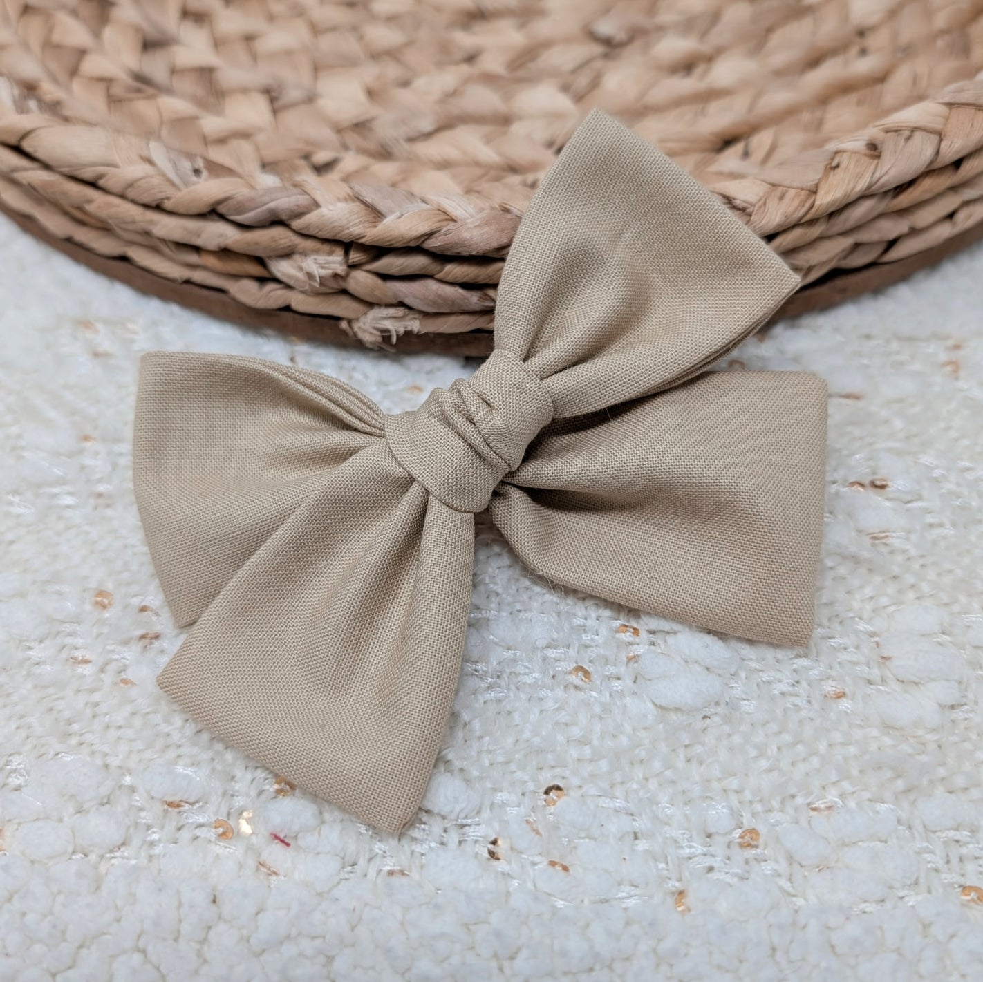 Beige bow on a textured surface with a woven mat in the background