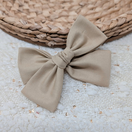 Beige bow on a textured surface with a woven mat in the background