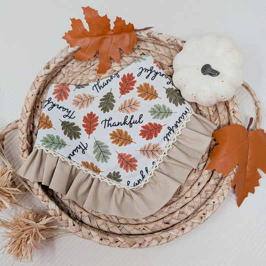 Decorative plate with autumn leaf pattern and 'Thankful' text on a woven mat with leaves and a pumpkin.